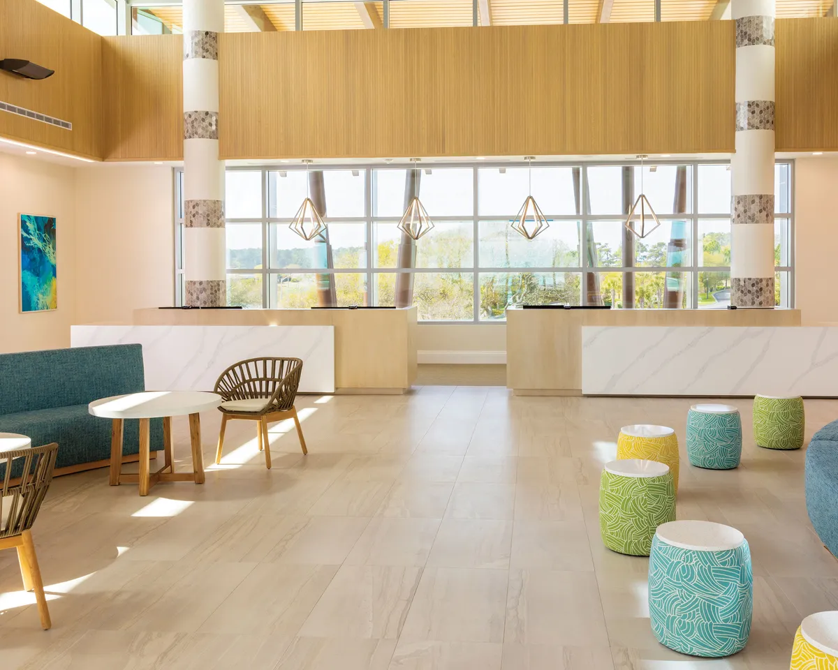 A bright entryway with large windows letting in natural light, colorful stools, and modern seating areas. The space feels welcoming and cheerful, setting the tone for the home-style haven described in the section.