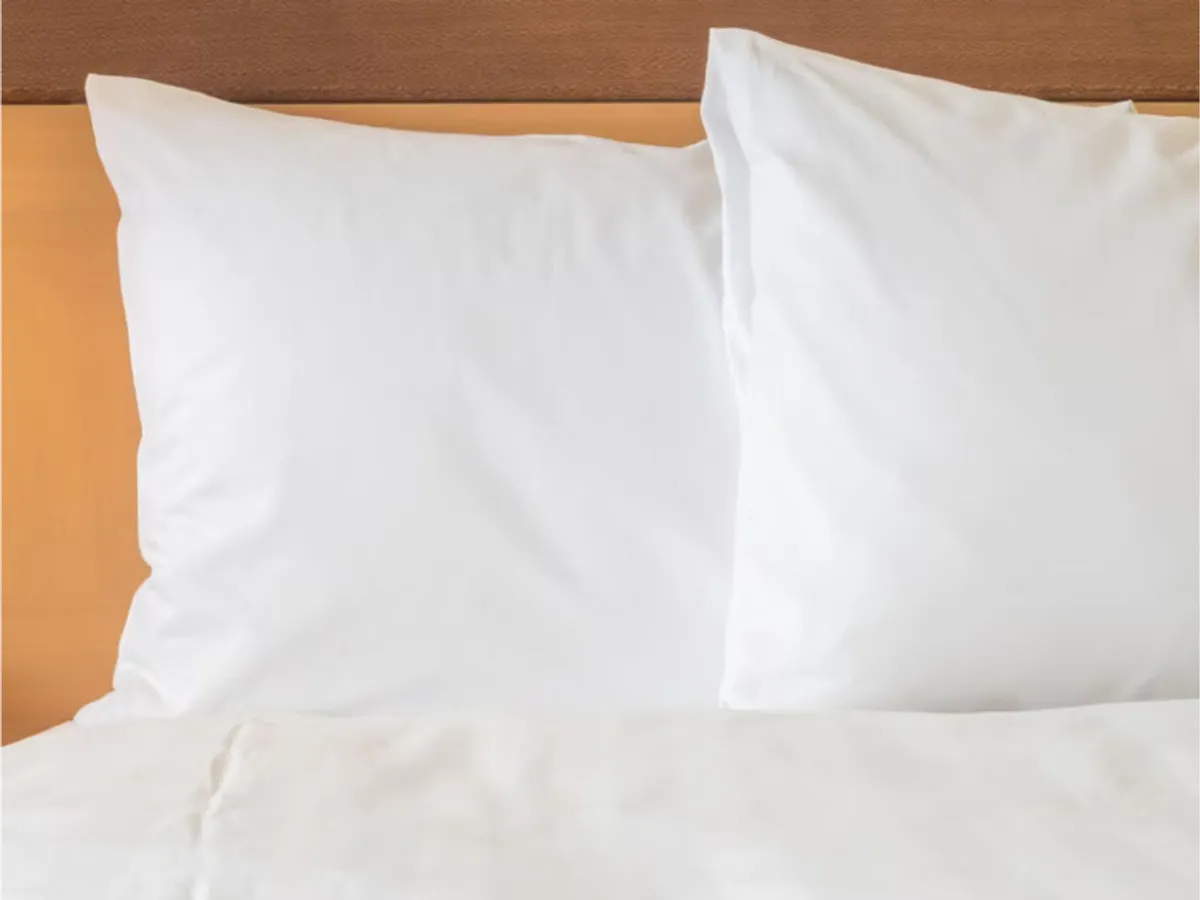 A serene bedroom scene featuring a plush king-sized bed with crisp white pillows and neatly arranged bedding. Soft natural light filters in, emphasizing the inviting comfort and tranquility of the space.