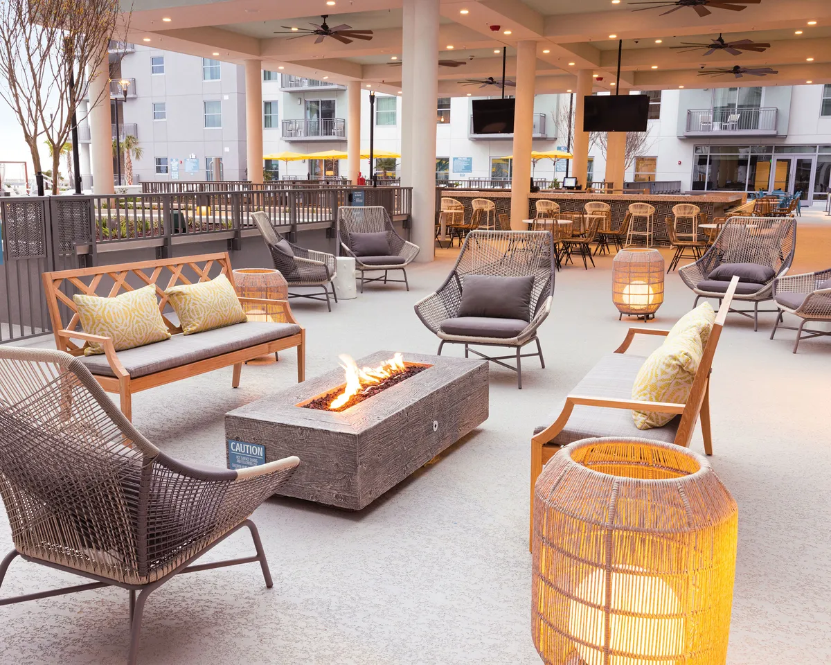 The image presents a cozy outdoor fire pit area with inviting seating arrangements, softly glowing decorative lanterns, and a communal atmosphere. Guests are pictured relaxing, engaged in intimate conversations, or enjoying quiet moments under the stars. The fire pit and ambient lighting create a sense of warmth and connection, perfect for evening gatherings or romantic moments.