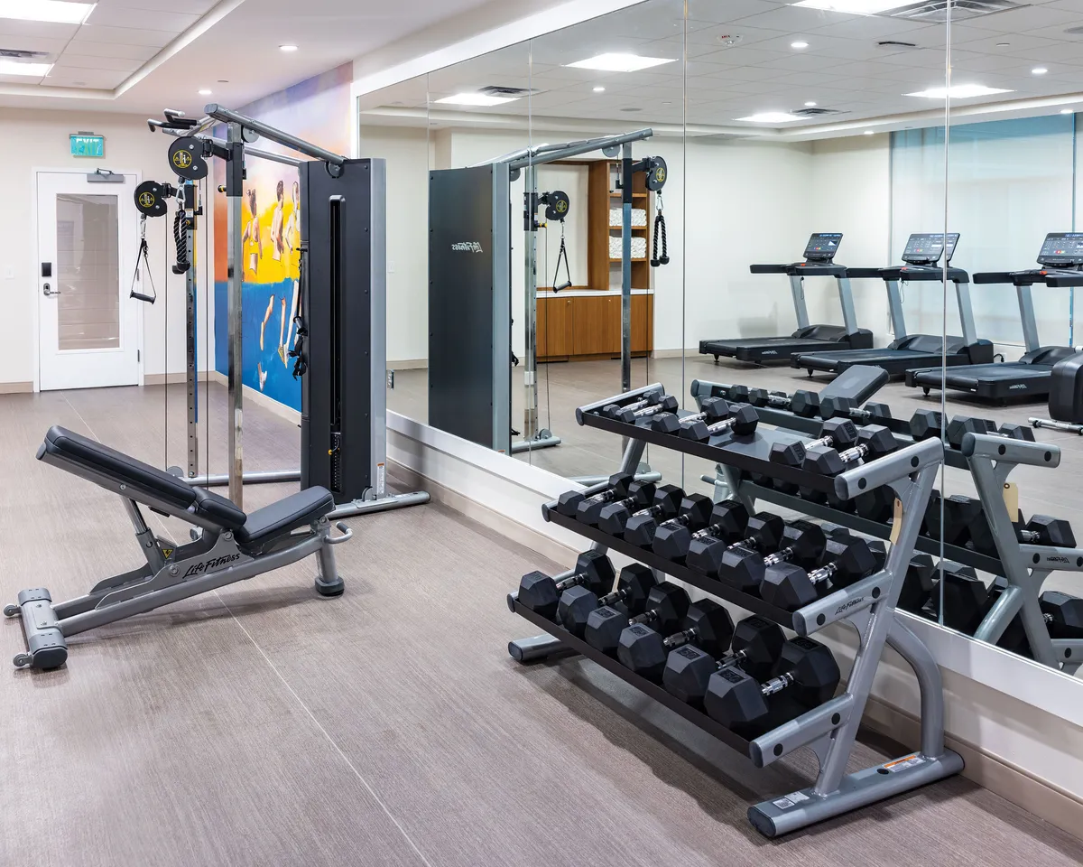 A state-of-the-art fitness center equipped with treadmills, weightlifting stations, and mirrors, designed for both strength training and cardio workouts. The space is clean, modern, and motivational, encouraging an active lifestyle for guests.