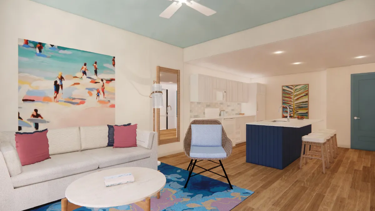 This image captures a vibrant open-concept living area with a sofa adorned with decorative pillows, a colorful artwork on the wall, an island bar with stools, and a lively rug. The scene exudes a cheerful and welcoming atmosphere, suggesting spaces for relaxation, socializing, and everyday living.